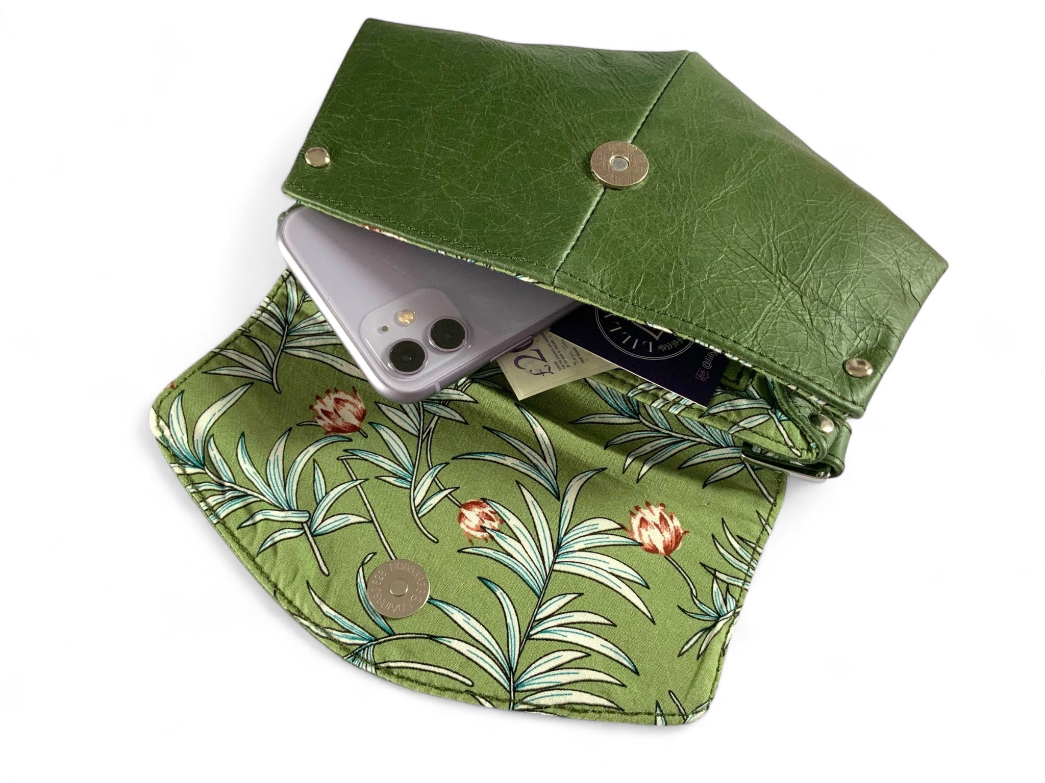 Forest green leather crossbody bag, with floral-patterned lining, with cash and a movbile phone on a white background