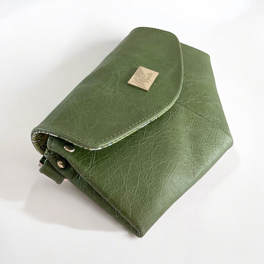 Green leather clutch bag with a Lilly & Jude logo badge on a white background