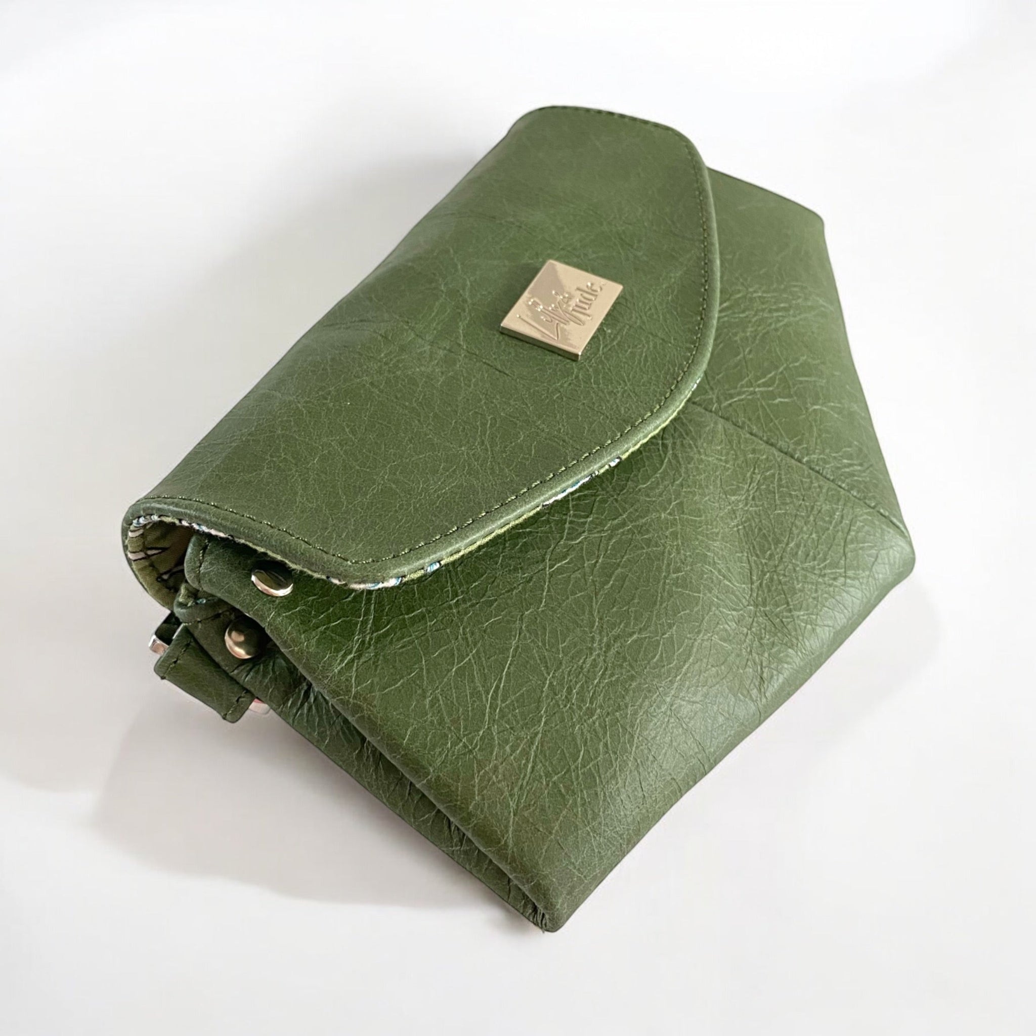 Green leather clutch bag with a Lilly & Jude logo badge on a white background