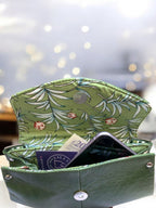 Green floral-patterned wallet lining with money and a mobile phone on a blurred background