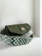 Unique, green leather bag with patterned strap on white background
