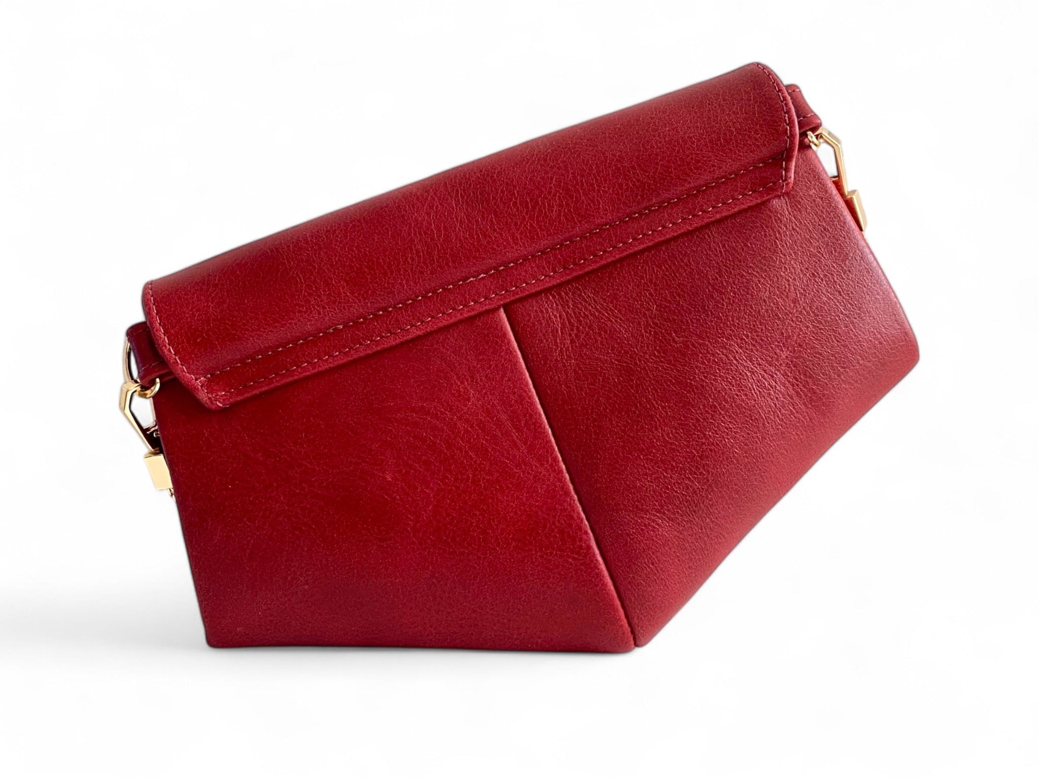 View of the back of a red leather handbag with gold accents on a white background