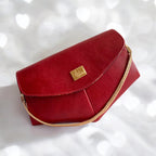 Red leather handbag with a gold chain and gold clasp and chain on a white background
