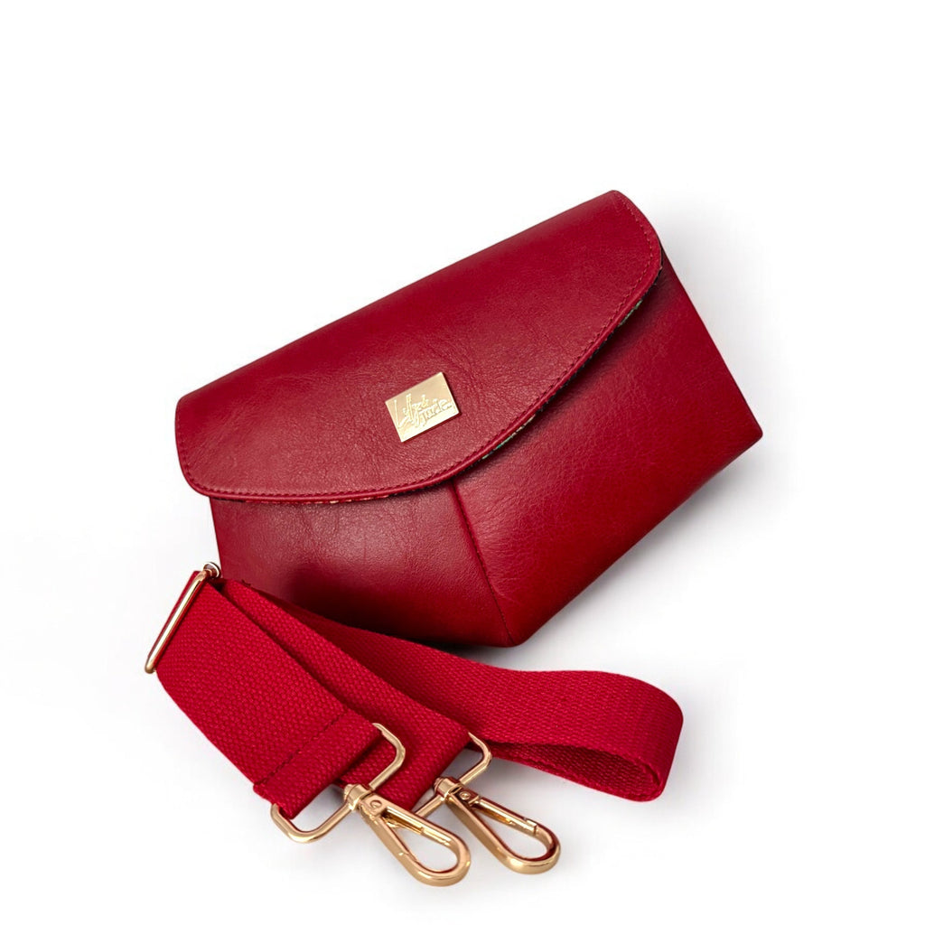 Red leather handbag with matching strap and gold clasp on a white background