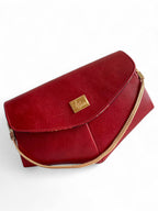 A red leather clutch with a gold chain handle against a white background.