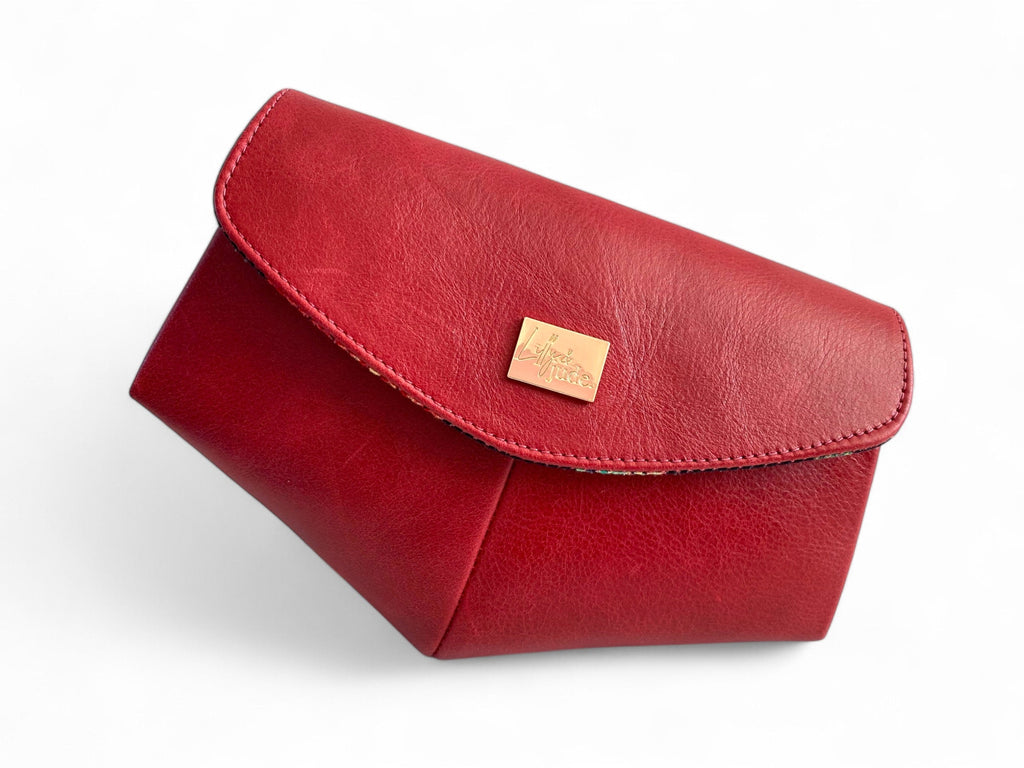 Red leather clutch bag with a gold tag on a white background.