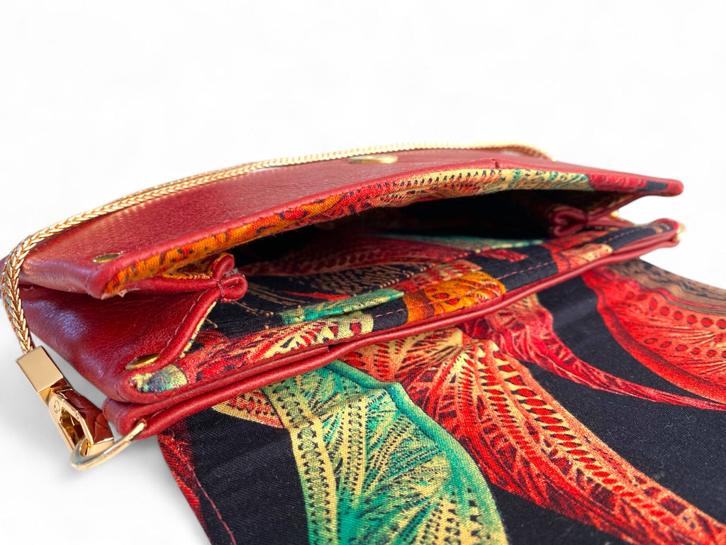 Red leather handbag with gold chain handle and open flap showing patterned lining interior.