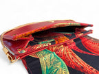 Red leather handbag with gold chain handle and open flap showing patterned lining interior.