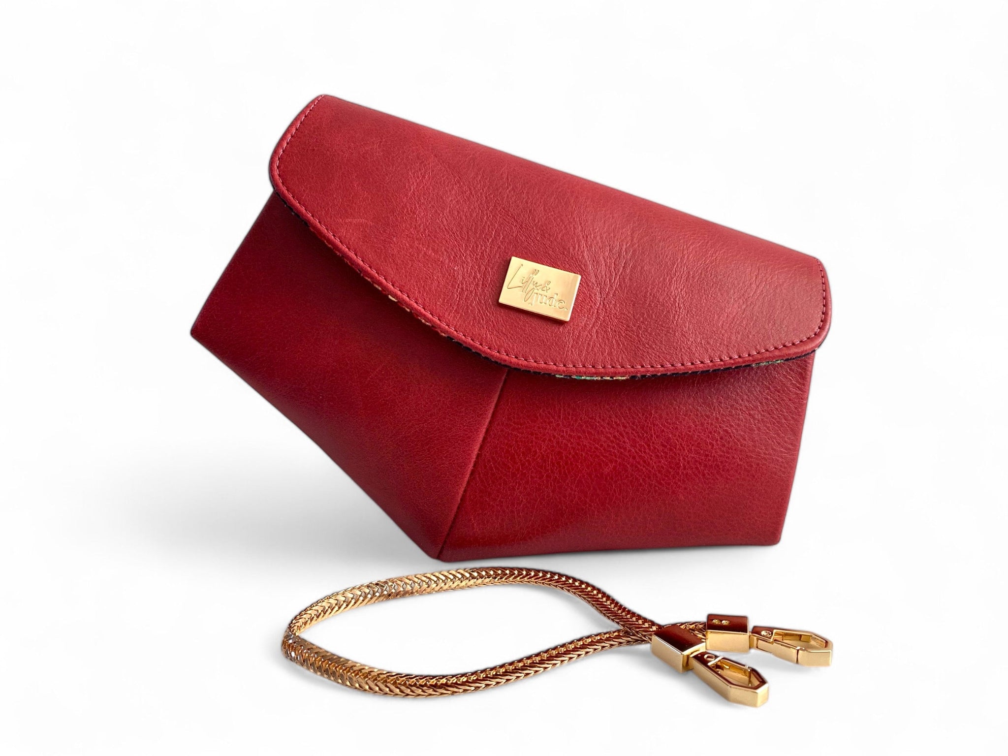 Red leather handbag with gold chain and clasp on a white background