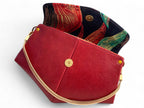 Red leather handbag with gold chain and decorative interior lining on a white background