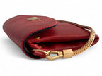 Side view of a red leather clutch bag with gold clasp and chain on white background