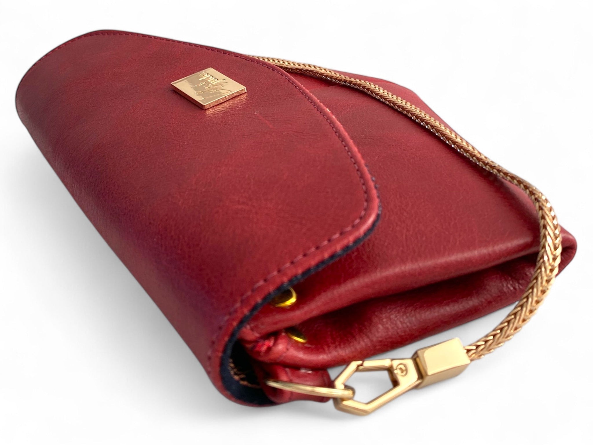 Red leather clutch bag with gold accents on a white background