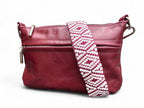 Burgundy coloured leather handbag with a white and burgundy patterned strap on a white background