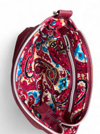 Open view of red leather crossbody bag, revealing a vibrant  paisley patterned lining
