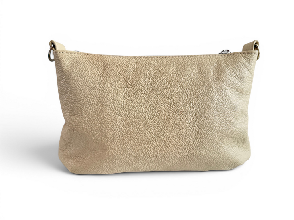 View of the back of a cream, butter yellow leather handbag on a white background