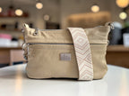 Beige handbag with a patterned strap on a blurred indoor background