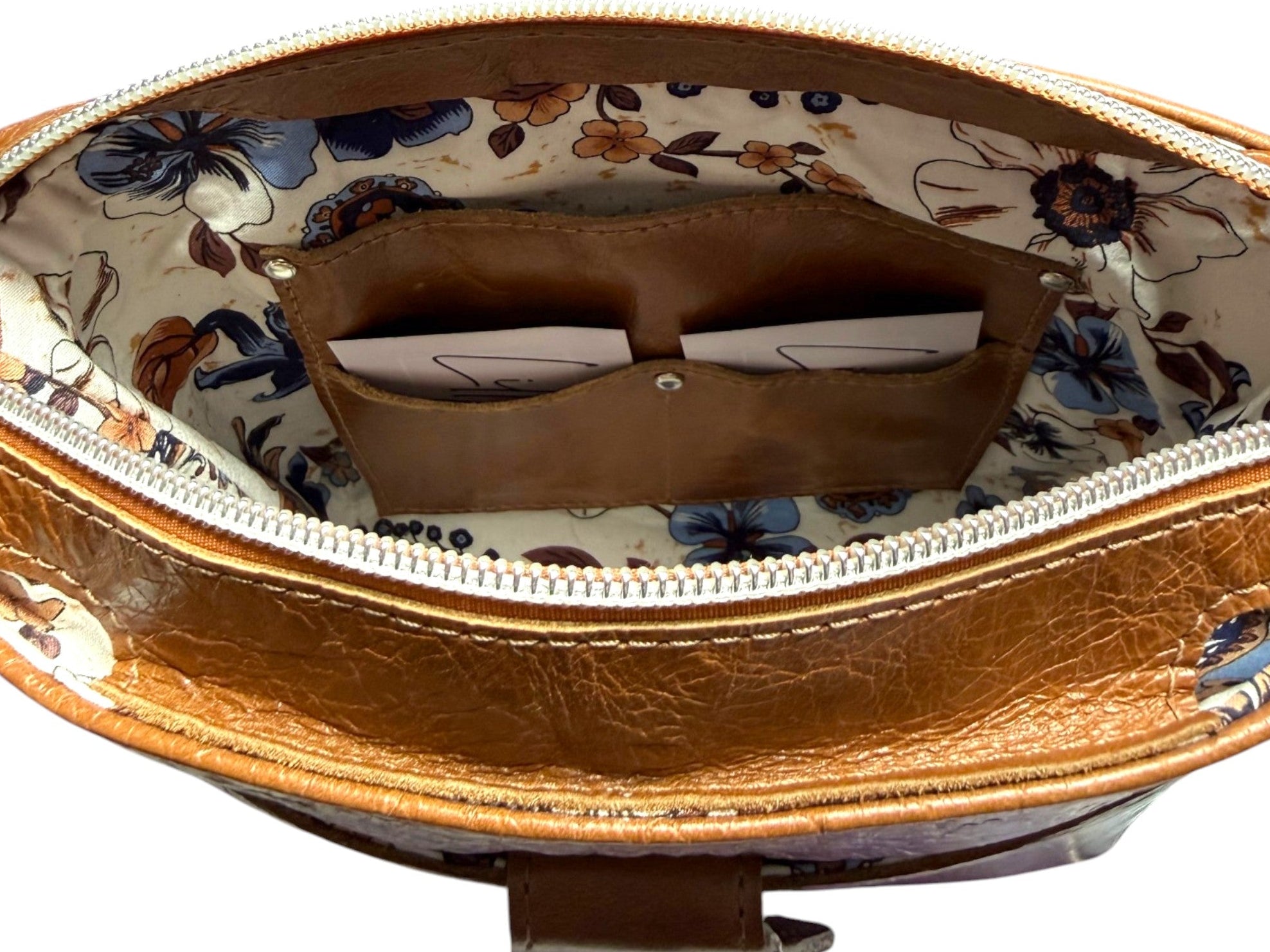 Close-up of a brown leather handbag with floral interior lining, showing the leather slip pocket and double card holder