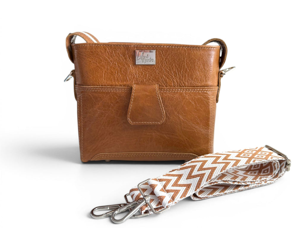 Tan brown leather bag with a patterned strap on a white background