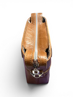 View of the top of a brown leather handbag with a silver zipper on a white background