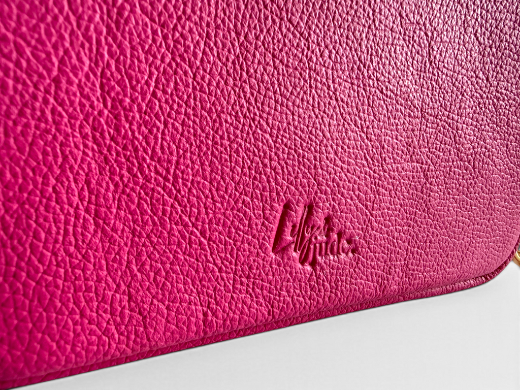 Close-up of a pink leather bag with the Lilly & Jude logo embossed into the leather, on a white background