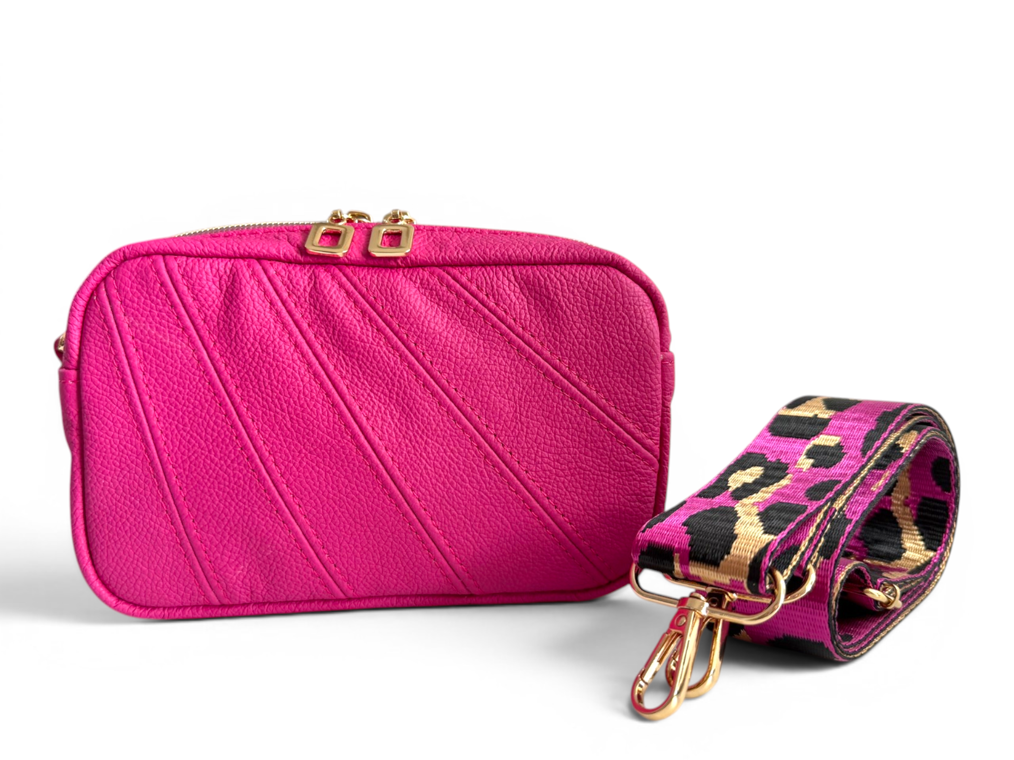 Fuschia pink leather crossbody handbag with gold accents and a matching strap featuring a leopard print design on a white background.