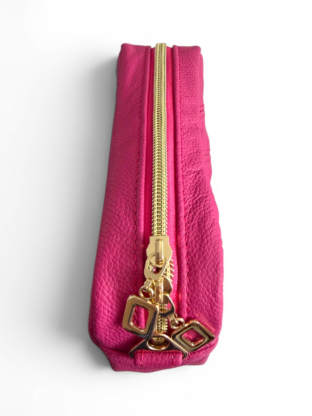 View of the top of a bright pink pouch with gold zipper and decorative pulls on a white background