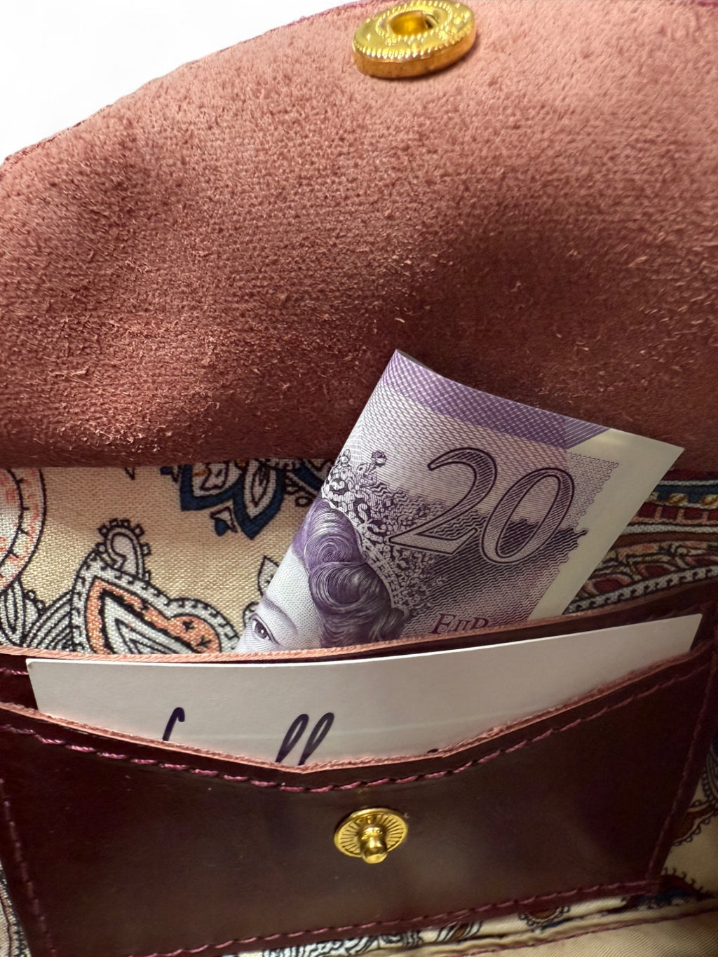 Close-up of an open integrated purse inside a compact crossbody bag, with a 20 pound note