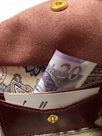 Close-up of an open integrated purse inside a compact crossbody bag, with a 20 pound note