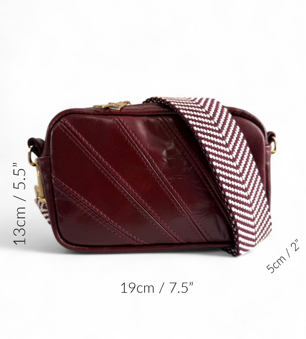 Maroon handbag with chevron patterned strap and measurement markings.