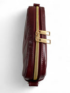Burgundy leather compact crossbody with gold zipper on a white background
