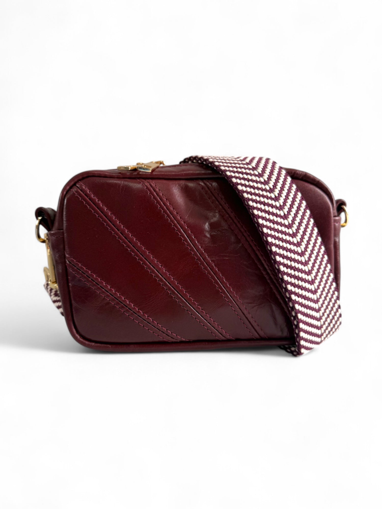 Burgundy leather compact crossbody handbag with a chevron patterned strap on a white background.