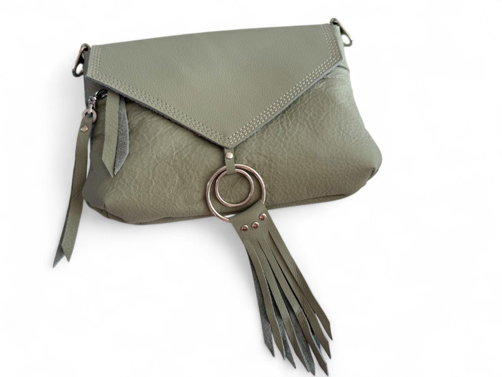 Pale olive green bag lying on a white background. The image shows the triangular shape of the flap and the detail of the silver rings and tassel that are attached to the flap. This bag is called Olivia and is hand made from eco-conscious materials, including genuine leather that was rescued from heading to landfill 