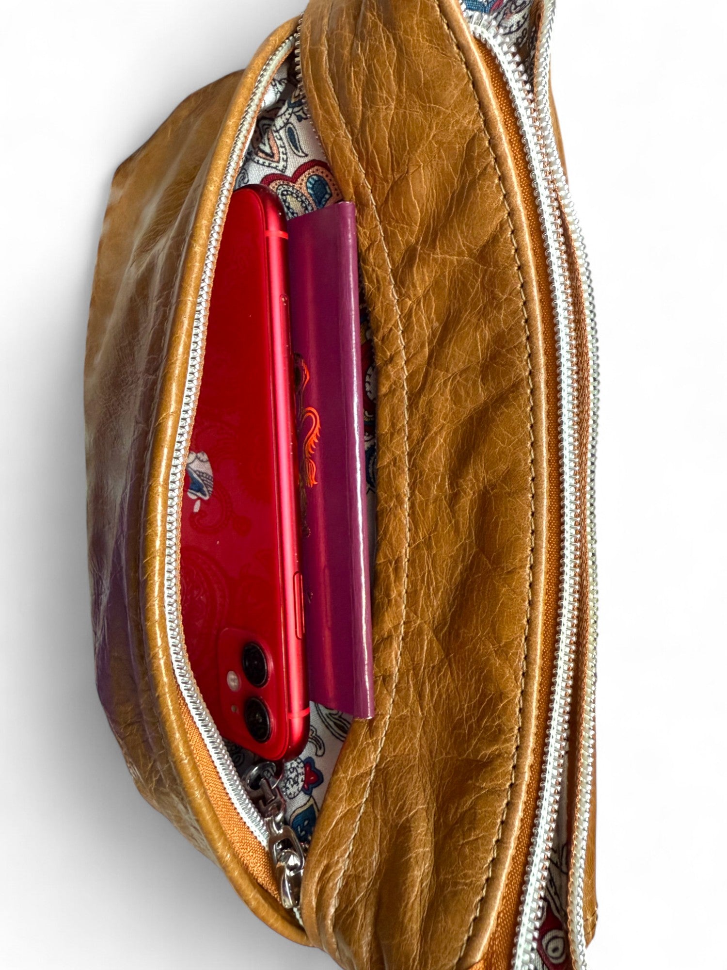 Tan brown crossbody bag, with the front pocket open to show a mobile phone and passport. The bag is a one-off and is hand crafted from rescued leather by Lilly & Jude
