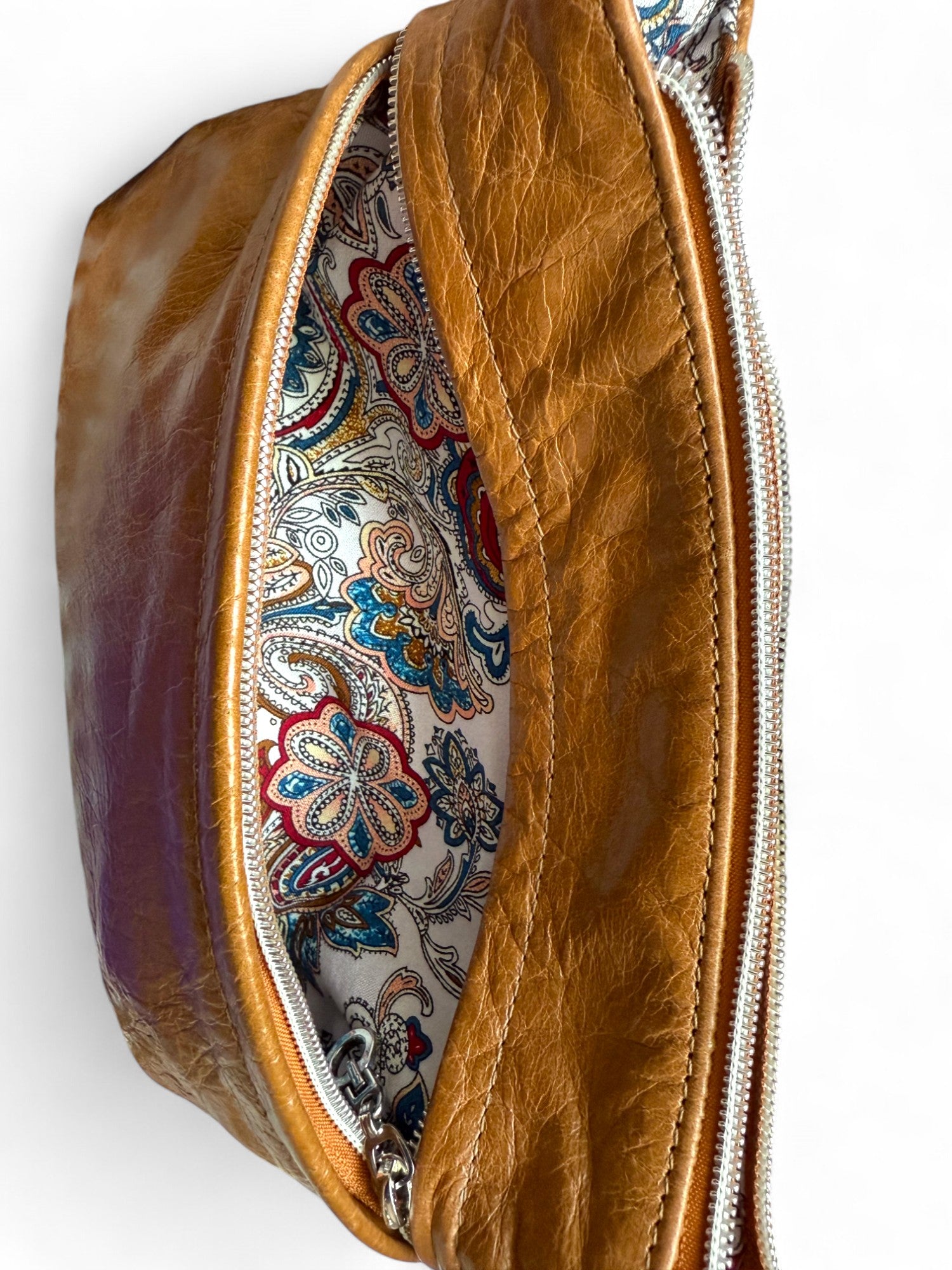 Slouchy crossbody bag, with the front zippered pocket  open to reveal the paisley patterned interior lining. This bag was hand crafted using tan coloured leather which has been rescued from heading to landfill