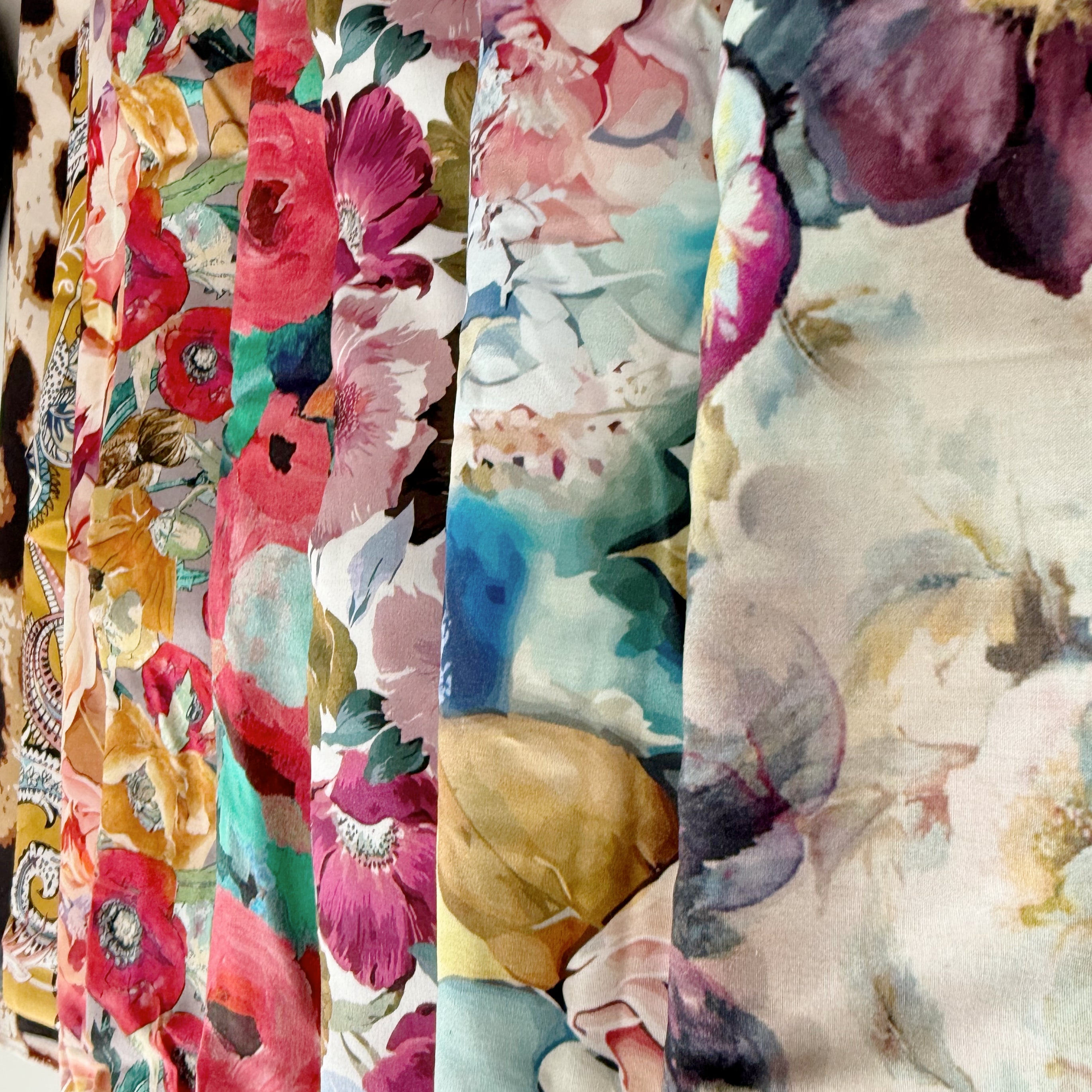 Bundles of fabric used for bag linings at Lilly & Jude, featuring floral, paisley, and leopard print patterns in various colours and textures